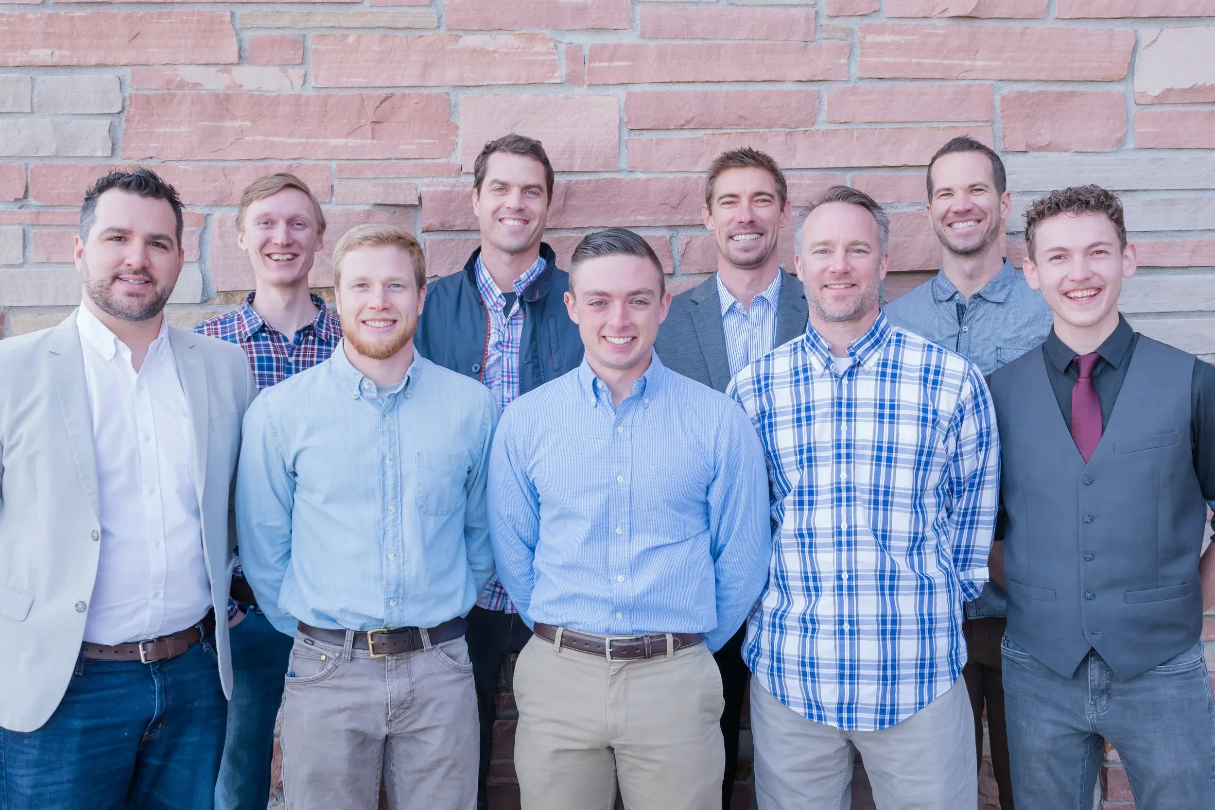 Men of Redeeming Grace Church gathered in front of the sandstone wall at Leprino Hall